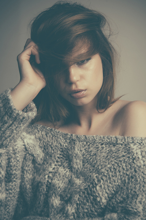 Beautiful blond woman with long hair and perfect makeup wearing knitted sweaterの写真素材