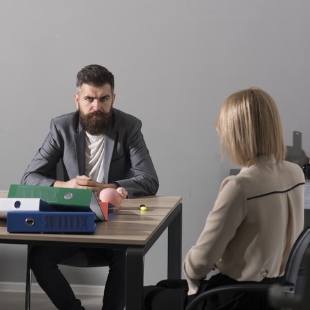 Bearded man and woman have business meeting. Businessman and businesswoman sit at office desk....