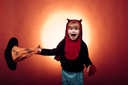 Halloween Witch with a carved Pumpkin and magic lights in a dark forest. Children play with pumpkins and treat. Halloween dresses and witch costumes and witch hats. Happy halloween.の写真素材