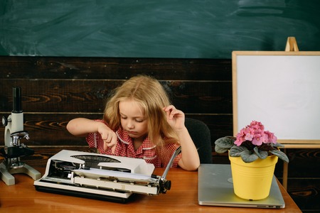 Pupil type on typewriter in school class. Elementary school pupil enjoy learning to typewrite.の写真素材