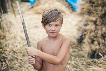 Boy on a breeze in an autumn village. Kids games in outdoor farm. Happy childhood in the childrens...