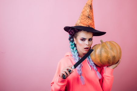 31 october. Make up and scary concept for woman. Celebration party. Beautiful young surprised woman in witches hat and costume holding pumpkin.の写真素材