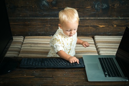 Child hacker type computer keyboard in office. Little computer hacker at work