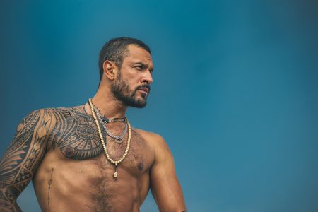 Muscular latin lover. Latin Man with muscular body looks seriously. Handsome brutal man on blue sky background. Portrait of brutal handsome male model.の写真素材