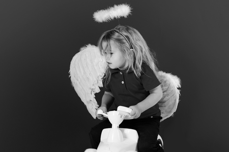 angel little boy on red background on car toyの写真素材