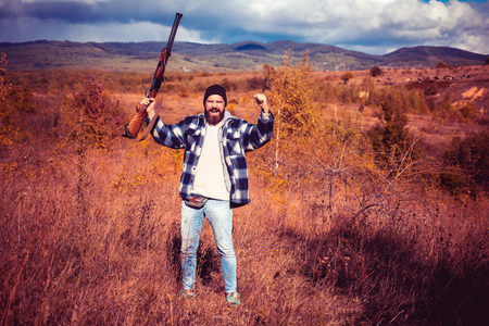 Hunter with shotgun gun on hunt. Autumn hunting season. Wildlife Hunting. Poacher in the Forest.