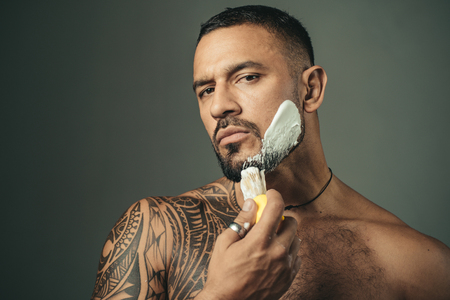 Razor sharp. Barber Shop Studios. Bearded man getting haircut by hairdresser and sitting in chair at...