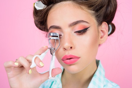 Pin up girl. vintage housewife woman curl eyelashes with tool. happy girl grooming in morning....