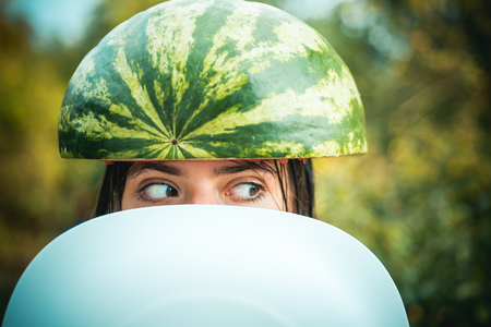 Very ridiculous girl writhes her face holding two halves of watermelon. Crazy people. Sale for entire autumn collection, incredible discounts and wonderful choice.の写真素材