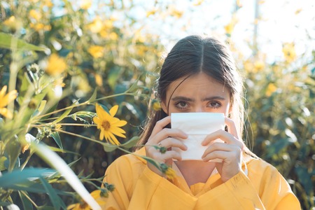 Young woman is going to sneeze. The girl suffers from pollen allergy during flowering and uses napkins.の写真素材