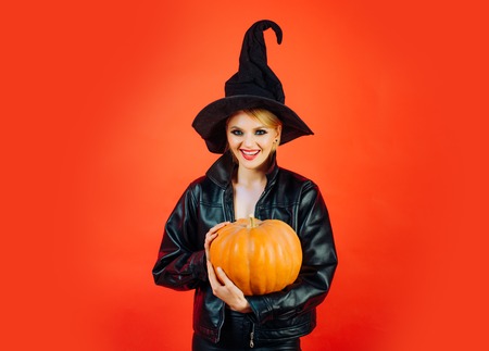 Happy Halloween. Happy gothic young woman in witch halloween costume. Witch posing with Pumpkin.