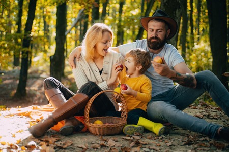 Camping with kids. Father mather and son camping. Parent teach baby. Dad mom and son playing together. Happy family eating apple in autumn park.の写真素材