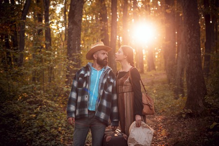Couple in love in autumn leaves. Beautiful young couple walking in autumn park. Young couple in love holding hands and walking through a park on a sunny autumn day.の写真素材