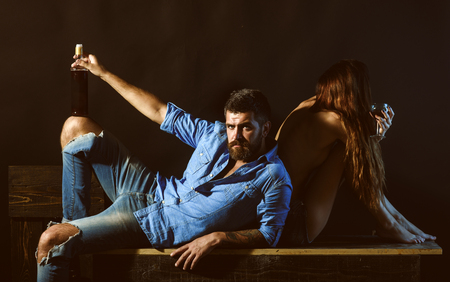 Men with sensual woman drink alcohol and enjoy the moment. Relaxing and enjoying concept. Romantic Couple sitting on the retro background with red wine.の写真素材