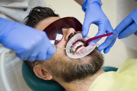 Remove decay from teeth and fill cavities. Repair cracked or fractured teeth and remove teeth. Dentist and patient.の写真素材