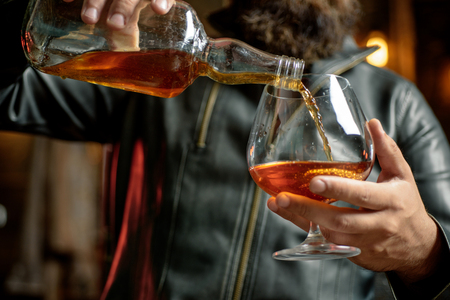 Whisky, brandy or cognac in glass. Alcohol addiction. Addictive group including alcohol cigarettes and drugs. Hard drugs and alcohol addict. Serious sad woman having alcohol addiction.の写真素材