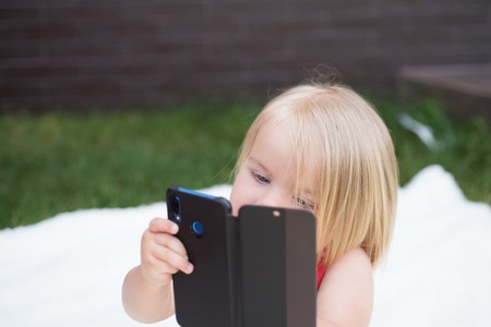 Cell phone dependency. Small child make phone call. Small girl use mobile phone. Girl child with...