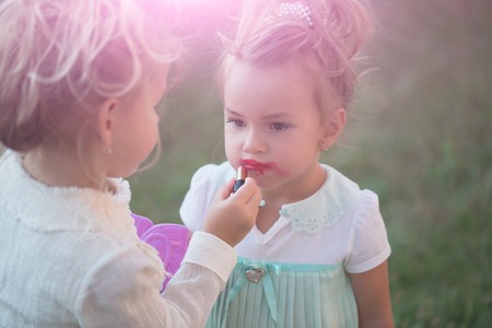 Girl do makeup for sister on green grass backgroundの写真素材