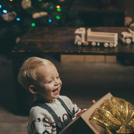 Smiling funny child in Santa hat holding Christmas gift in hand. Cute Baby, Merry Christmas. Merry christmas and Happy new year.の写真素材