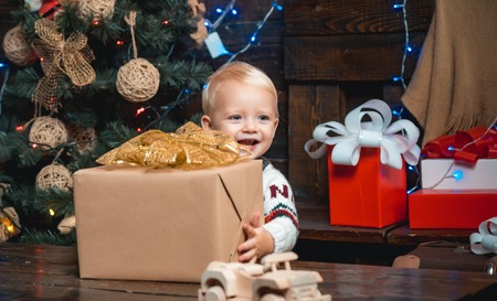 New year presents in gift box for kids. Smiling funny child in Santa hat holding Christmas gift in hand.の写真素材