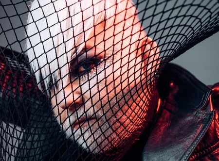 Fashionable look. BDSM fashion accessory. Transgender man cover face with fishnet. Male makeup look. Fetish fashion. Heterosexual man with male makeupの写真素材