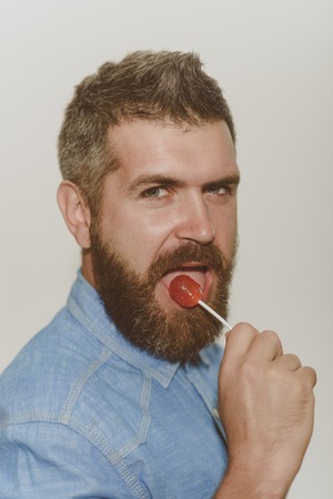 Feeling playful. Bearded man lick candy. Man with beard and mustache. Man of fashion. Beard fashion trend. Barber shop or barbershop. My barber is the best. He found the beard thats right for himの写真素材