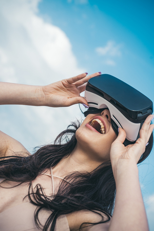 Woman getting experience using VR-headset glasses. Happy girl using VR headset. Digital future innovation. Visual reality concept. Woman with glasses of virtual reality. New technology. Its so realの写真素材