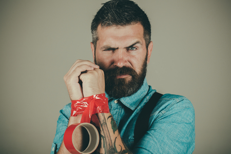 Mind control and propaganda. International Human Right day. Concept freedom of speech and press. censorship. Brutal bearded male. man wrapping mouth by adhesive tape. free me. restricted and limited.の写真素材