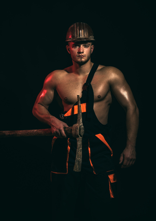 Caution, under construction. Muscular man worker. Man miner with mining equipment.の写真素材
