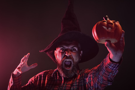 Halloween hipster in wizard hat holding pumpkinの写真素材