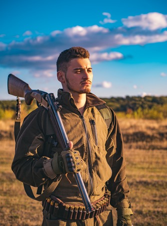 Hunter with shotgun gun on hunt. Cartridges shotgun. Track down. Close up Portrait of hamdsome Hunter.の写真素材
