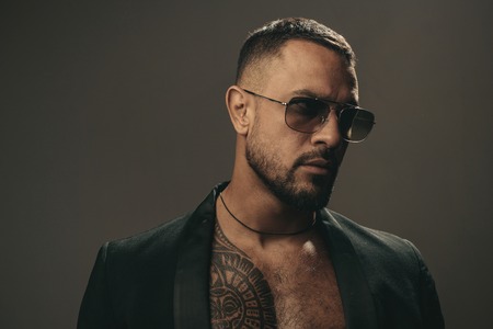 Mans fashions, stylish male model. Closeup man portrait. Man face. Handsome bearded man - face half on grey background.の写真素材