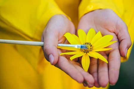 Spring painting. Yellow spring mood. Flower on hands. Girl painting Flower. Spring sensual woman with flower.の写真素材