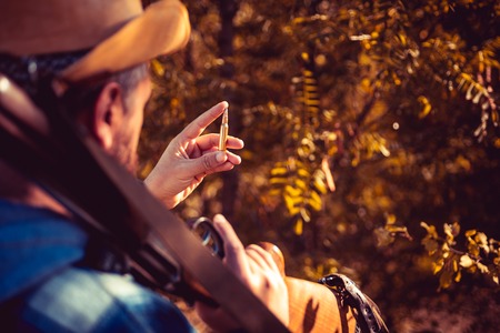 Hunting cartridge. Vintage Texas ranger with cartridge. Man is charging a hunting rifle. Hunter with...