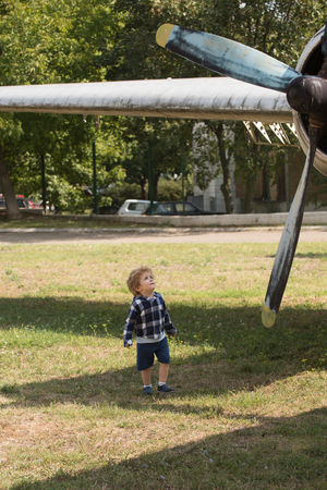 The world is yours to explore. Small child at plane field. Cute boy child on vacation trip. Small kid on summer vacation. Airplane tour and travel. Enjoying summer travel. Travelling by air.の写真素材