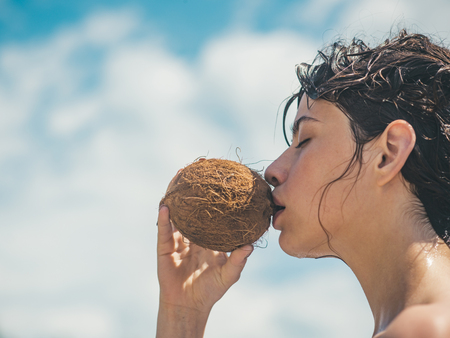 coconut oil production. coco milk. Clean eating diet, vegetarian and vegan. Woman is moisturizing her skin with a coconut cream. drinking beach cocktail. woman drinking coconut juice. summer vacation.の写真素材