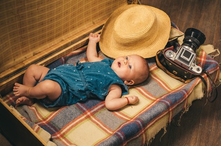 Lets go with me. Childhood happiness. Photo journalist. Small girl in suitcase. Traveling and adventure. Sweet little baby. New life and birth. Family. Child care. Portrait of happy little child.の写真素材