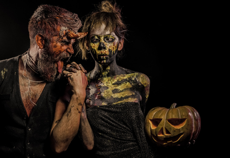 Halloween woman skeleton and man with horns hold pumpkinの写真素材