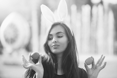 Cheerful girl with rosy bunny ears posing with colored eggs,の写真素材