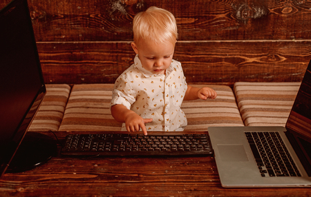 Boy programming on computer with multiple monitors and laptop on desk. Developing programming and coding technologiesの写真素材
