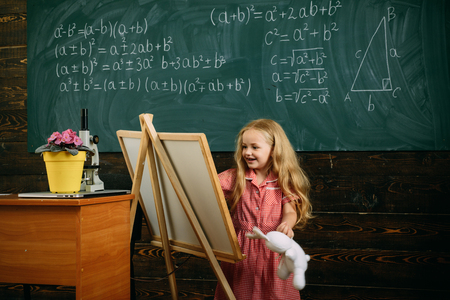 Creative artist painting on studio easel. Little artist girl creating picture in class.