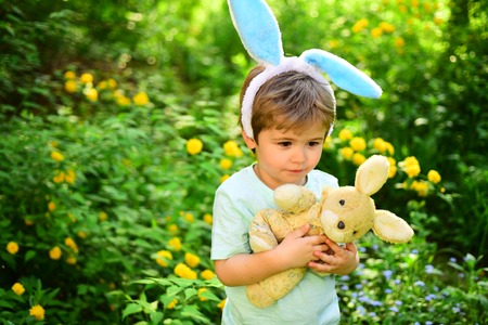 Egg hunt on spring holiday. Little boy child in green forest. love easter. Family holiday. Happy easter. Childhood. Rabbit kid with bunny ears. Hare toy. Easter fun.の写真素材