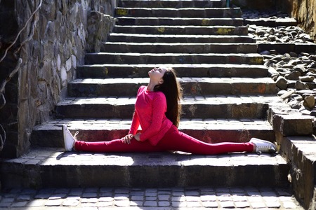 Increasing flexibility. Active child training on spring day. Little girl doing split outdoor. Small...