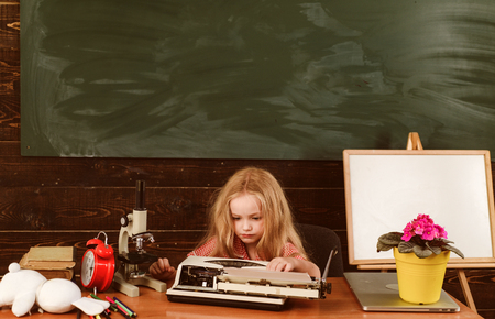 Little girl typewrite on vintage typewriter in school. Child typewrite keys on vintage machine in classroom.の写真素材