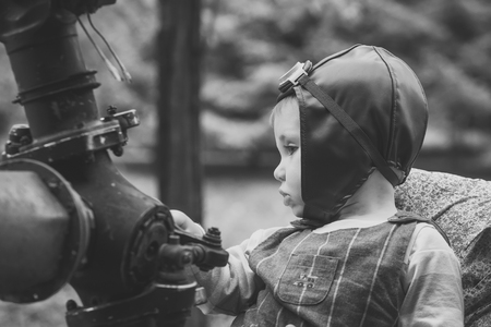 Child pilot in aviator helmet sitting at metal gearの写真素材