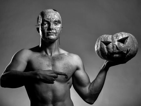 muscular man in mask with pumpkinの写真素材