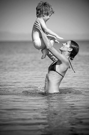 Happy family on Caribbean sea. mother with son swim in water. Summer vacation and travel to ocean. Maldives or Miami beach activity joy. Mothers day holiday of little boy in hands of woman parent.の写真素材