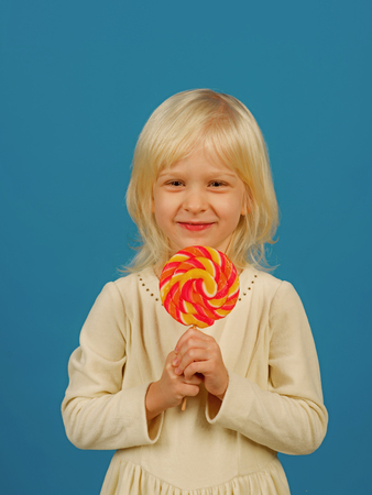 Bold hard candy creation. Small child with sweet lollipop. Small girl hold lollipop on stick. Happy candy girl. Happy childhood foodの写真素材