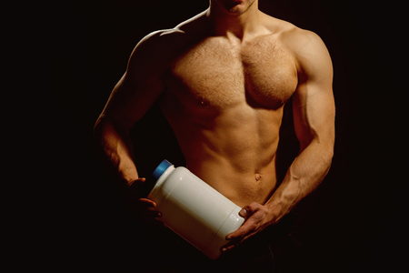Vitamins are organic. Sport nutrition and vitamin diet. Athletic man hold vitamin bottle in strong arms. Man use sport vitamin supplements for muscle building. Healthy diet and fitnessの写真素材