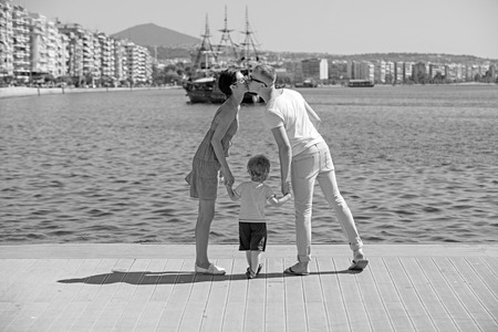 Child with father and mother. child with kissing parents in bay.の写真素材
